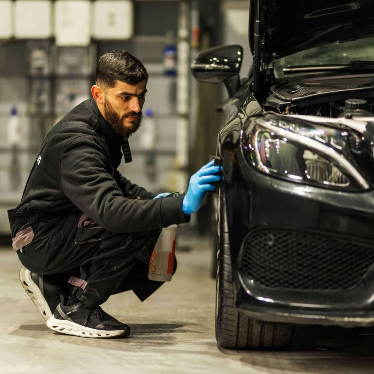 Medewerker werkt aan de voorzijde van een zwarte auto