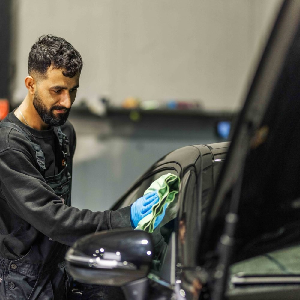 Medewerker neemt de carrosserie van een auto af met een doek
