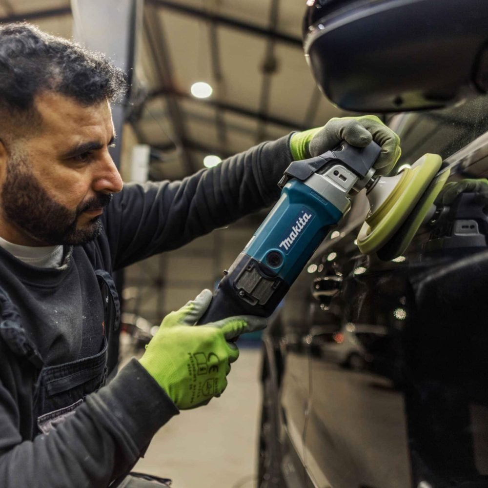 Medewerker polijst de buitenzijde van een auto
